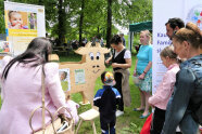 Mehrere Personen stehen um hölzerne Kuh an einem Infostand im Freien