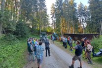 Menschen stehen auf einem Waldweg und schauen einer Maschine zu: Vorführung Wegepflege.