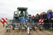 Traktor mit digitalem Hackgerät fährt an Zuschauern vorbei 