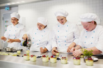 Vier Schülerinnen stellen Nachtisch in Großküche her 
